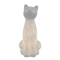 a white cat sitting on top of a table next to a light up candle holder