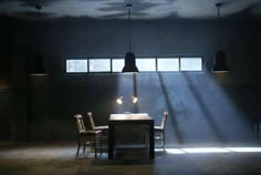 two chairs and a table in a dark room with light coming through the window,