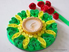 a paper quilled candle surrounded by plastic flowers