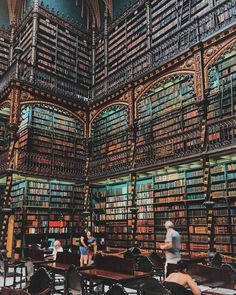 people are sitting at tables and reading books in a library filled with lots of books