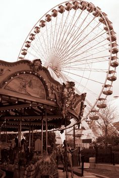 an old fashioned carousel with a ferris wheel in the background