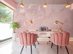 two pink chairs sitting next to each other in front of a desk with lights on it