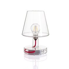 a lamp with a red cord attached to it on top of a glass table light