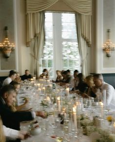 a group of people sitting around a table with wine glasses and candles in front of them