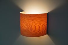 a wall light with a wooden shade on it's side in a dark room