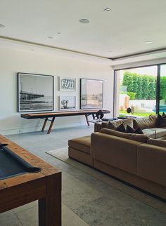 a living room filled with furniture and a pool table in front of a large window