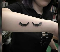 a woman's arm with two eyelashes tattooed on the left side of her arm