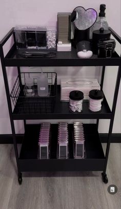 a black shelf filled with lots of items on top of a hard wood floored floor