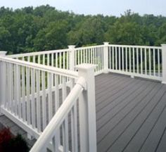 a deck with white railings and trees in the background