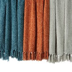 four different colors of scarves hanging on a line with one folded over the other