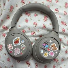 headphones with stickers on them laying on a floral print bed sheet in front of a pink flowered blanket