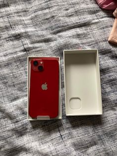 an apple phone in its box on a bed with the lid open and it's empty