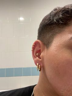 a close up of a person with ear piercings and a tiled wall in the background