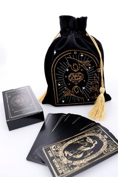 a black velvet bag with gold foilwork on the front and sides, sitting next to two playing cards