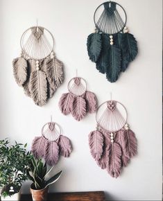 three wall hangings with different colored feathers and beads on the sides, one is made out of metal wire