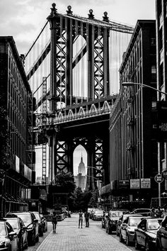 black and white photograph of people walking under the manhattan bridge