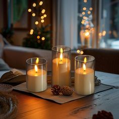 three lit candles sitting on top of a wooden table