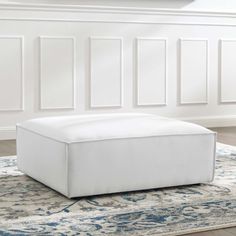 a white ottoman sitting on top of a rug