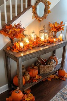 a table with candles and pumpkins on it next to a stair case filled with fall leaves