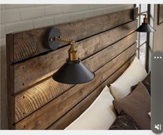 a wooden headboard with two lights on it and pillows in the foreground, against a white brick wall