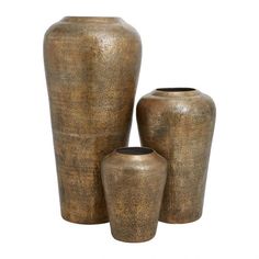 three vases sitting next to each other in front of a white background and one is gold