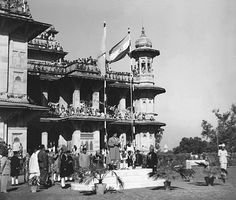 an old black and white photo of people in front of a building with many flags