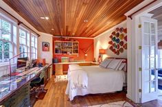 a bedroom with wooden ceiling and white bed