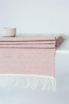 a pink towel with fringes hanging from it's end on a white shelf