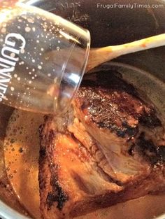 a glass being poured into a pot filled with meat