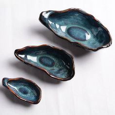 three blue bowls sitting on top of a white table