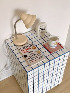 a table with a lamp, coffee cup and other items on it in the shape of a cube