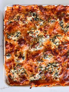 a casserole dish with cheese and spinach on top, ready to be eaten