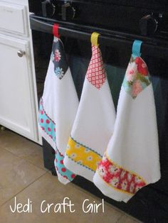 three kitchen towels hanging on the oven door knobs and in front of an oven