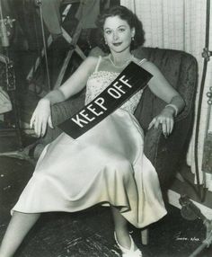 an old black and white photo of a woman sitting in a chair with a sash