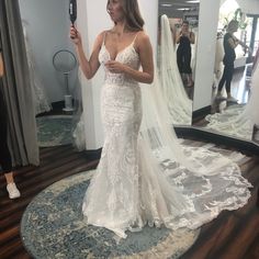 a woman taking a selfie in front of a mirror wearing a white wedding dress