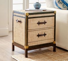 a table with two drawers sitting on top of a wooden floor next to a white couch