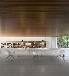 a long table with four chairs in front of it and a book shelf on the other side