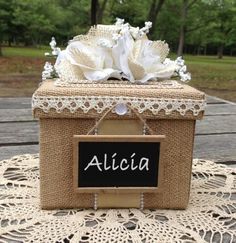 a small box with some flowers in it on top of a doily covered table