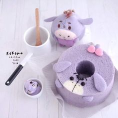 a purple cake sitting on top of a white table next to a cup and spoon