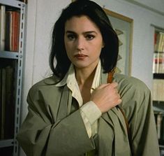 a woman standing in front of a bookshelf with her hand on her shoulder