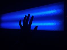 a person's hand in front of a large screen with blue lights on it