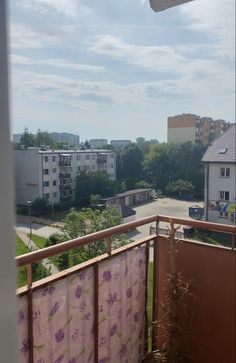 a balcony with curtains on it and buildings in the background