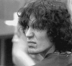 black and white photograph of a man with curly hair looking off into the distance,