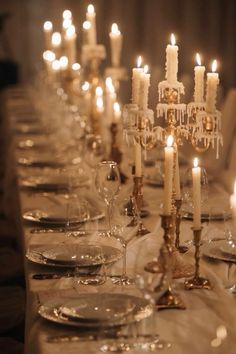 a long table is set with candles and plates for an elegant dinner or party event