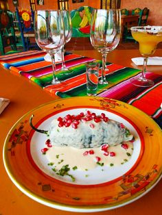 a plate with some food on it sitting on a table next to wine glasses and plates