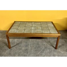 a wooden table sitting on top of a cement floor next to a yellow wall and planter