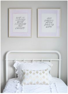 two framed pictures on the wall above a white bed with ruffles and pillows