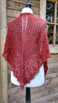 a red knitted shawl sitting on top of a white mannequin