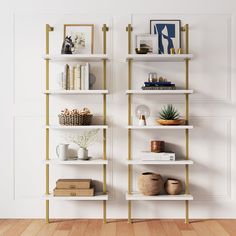 a white and gold book shelf with books on it next to a wall mounted plant