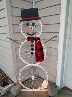 a snowman made out of bicycle wheels on the side of a house